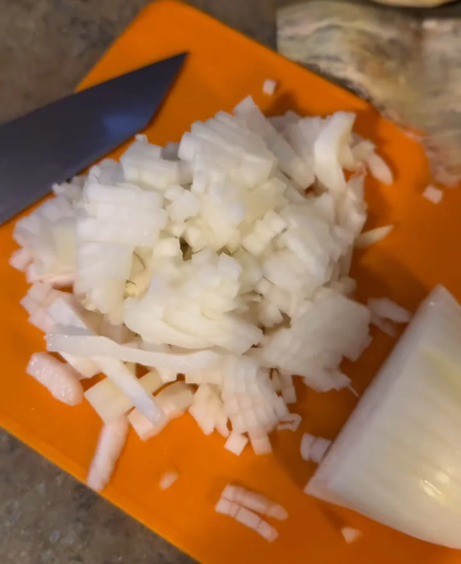 Chopped onion on a cutting board while James prepares his one-pot sauce.